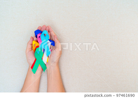 World cancer day, February 4. Hand holding blue, red, teal, white, pink, navy blue and yellow ribbons for supporting people living and illness. Healthcare and Autism awareness day concept 97461690