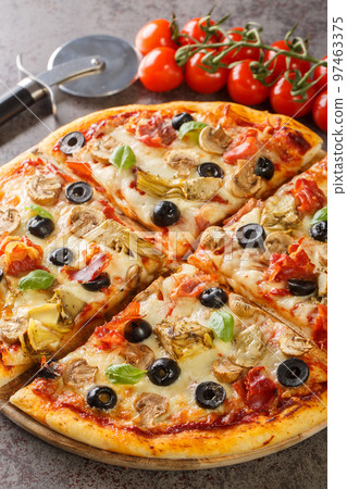 Freshly baked capricciosa pizza with artichokes, prosciutto ham, olives, mushrooms and cheese close-up on a wooden board. Vertical 97463375