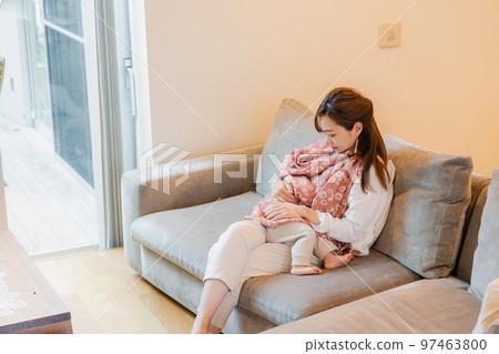 mother breastfeeding baby on sofa 97463800