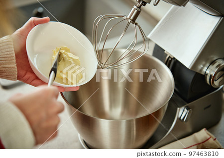 Woman preparing dough for cake at home kitchen. Female hands use electric mixer. Modern kitchen household appliances Woman preparing dough for cake at home kitchen. Female hands use electric mixer. Modern kitchen household appliances 97463810