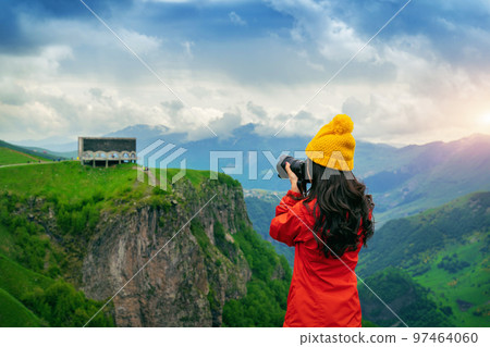 Tourist take a photo near Russia Georgia friendship monument on the georgian military road at the Jvari pass, Georgia. 97464060