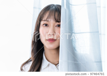 Woman sticking her face out of lace curtains Woman sticking her face out of lace curtains 97464781