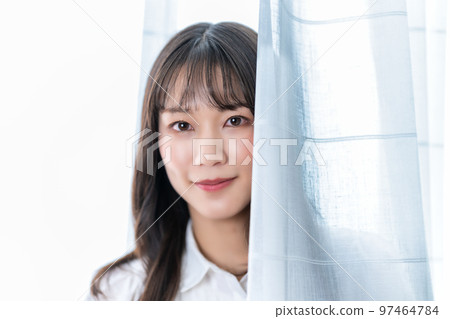 Woman sticking her face out of lace curtains 97464784
