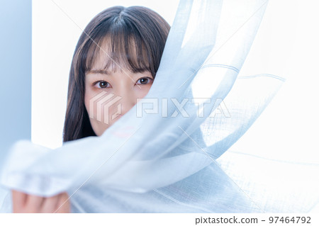 Woman sticking her face out of lace curtains 97464792