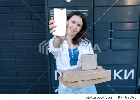 Happy woman holding mobile phone with white screen mockup for inscription and holding many different cardboard boxes with online order, satisfied with fast delivery, buying high quality products. 97465363