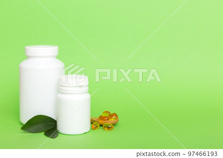Omega-3 capsules lie in white bottle on a table with green leaves background. Fish oil tablets. Biologically active additives. omega 6, omega 9, vitamin A, E, D, vitamin D3 top view with copy space Omega-3 capsules lie in white bottle on a table with green leaves background. Fish oil tablets. Biologically active additives. omega 6, omega 9, vitamin A, E, D, vitamin D3 top view with copy space 97466193