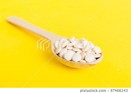 Heap of white pills on colored background. Tablets scattered on a table. Pile of red soft gelatin capsule. Vitamins and dietary supplements concept 97466243