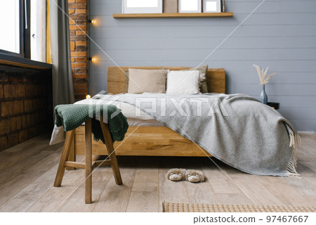 Green blanket on the stool by the bed in the bedroom in the Scandinavian style 97467667