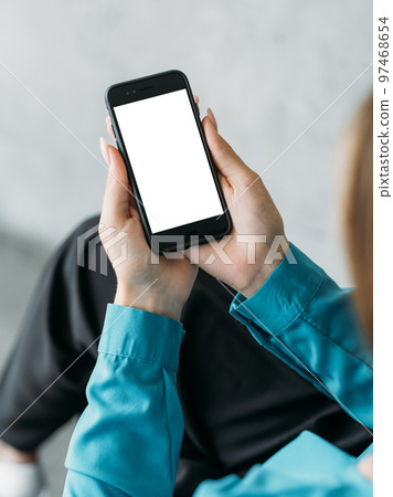 Online conference. Office woman. Mobile mockup. Female hands holding smartphone with blank screen in light room interior. Online conference. Office woman. Mobile mockup. Female hands holding smartphone with blank screen in light room interior. 97468654