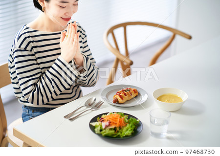Woman starting a meal in the dining room at home 97468730