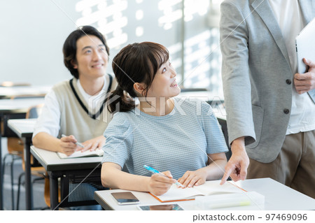 A female college student taught by a teacher in a university classroom 97469096