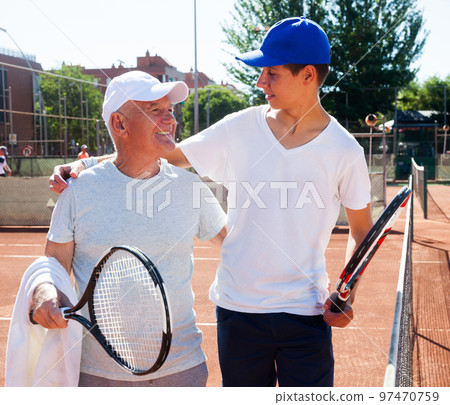 grandfather and grandson talking on court playing tennis grandfather and grandson talking on court playing tennis 97470759