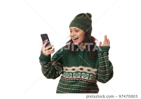 African American charming woman in warm woolen clothes, holds smartphone, enjoys online conversation by video link, isolated on white background. Copy advertising space. Communication across distance 97470803