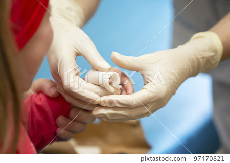 The hands of the doctor bandage the sore finger with a bandage of the child. Injury and wound on the finger in children The hands of the doctor bandage the sore finger with a bandage of the child. Injury and wound on the finger in children 97470821