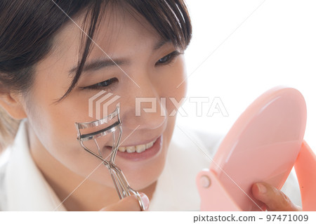 一個年輕女人用睫毛夾做眼妝 97471009