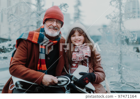 Portrait of grandfather and granddaughter in winter at outdoor ice skating rink. 97471164