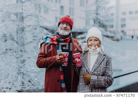 Happy senior couple enjoying christmas market, drinking muled wine. 97471170