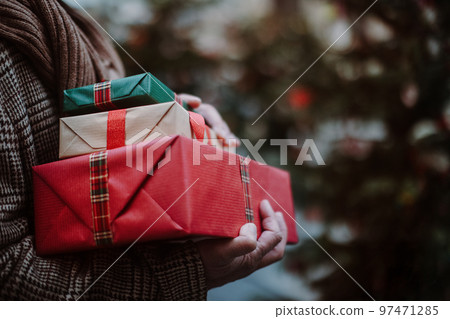 Close-up of man holding gifts, outdoor at Christmas market. 97471285