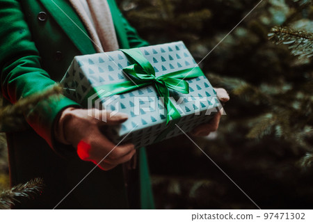 Close-up of woman holding gifts, outdoor at Christmas market. 97471302