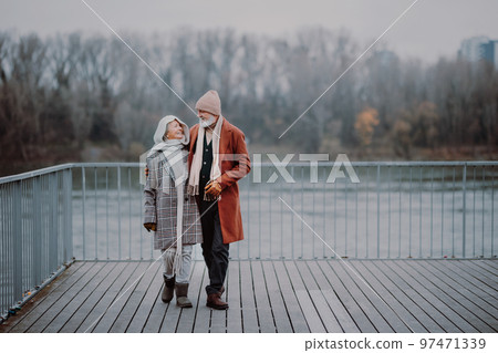 Elegant senior couple walking near the river, during cold winter day. 97471339