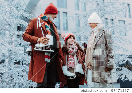 Seniors with their granddaughter in winter at outdoor ice skating rink. Seniors with their granddaughter in winter at outdoor ice skating rink. 97471357