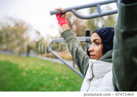 Young muslim woman in sports hijab doing work out in outdoor training ground. Young muslim woman in sports hijab doing work out in outdoor training ground. 97471464