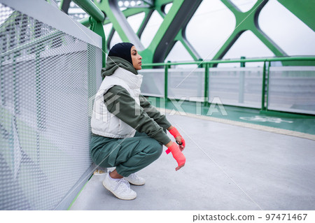 Young muslim woman having break during morning jogging. Young muslim woman having break during morning jogging. 97471467