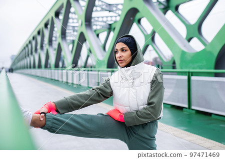Young muslim woman doing stretching before morning jogging. Young muslim woman doing stretching before morning jogging. 97471469