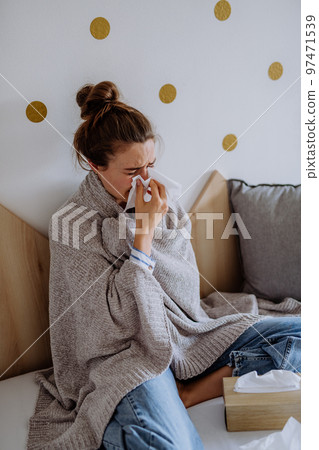 Sick woman sitting in bed, having a cold. 97471539