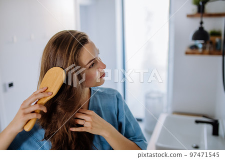 Young woman taking care of her hair, morning beauty routine concept. 97471545