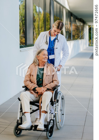 Young woman doctor taking care of senior woman at wheelchair. Young woman doctor taking care of senior woman at wheelchair. 97471666