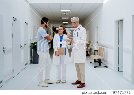 Team of doctors discussing something at hospital corridor. Team of doctors discussing something at hospital corridor. 97471771
