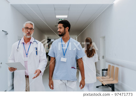 Doctors, colleagues discussing something at hospital corridor. Doctors, colleagues discussing something at hospital corridor. 97471773