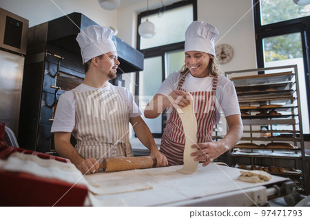 Man with down syndrom helping prepair bread in bakery with his colleague. Concept of integration people with disability into society. Man with down syndrom helping prepair bread in bakery with his colleague. Concept of integration people with disability into society. 97471793
