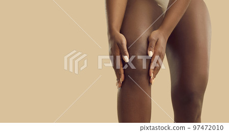 Young black woman suffering from knee pain due to rheumatoid arthritis or leg injury Young black woman suffering from knee pain due to rheumatoid arthritis or leg injury 97472010