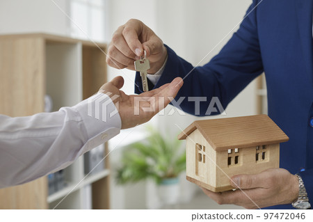 Real estate agent hands over key to customer after signing home purchase agreement. 97472046