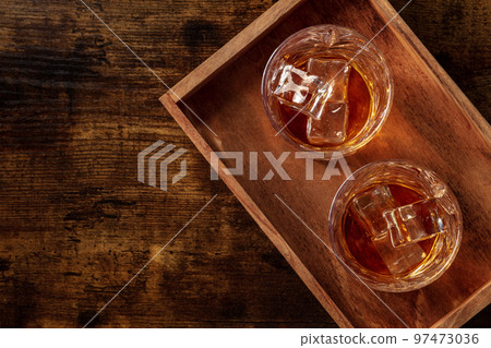 Whiskey in glasses with ice. Bourbon whisky on rocks on a dark background 97473036