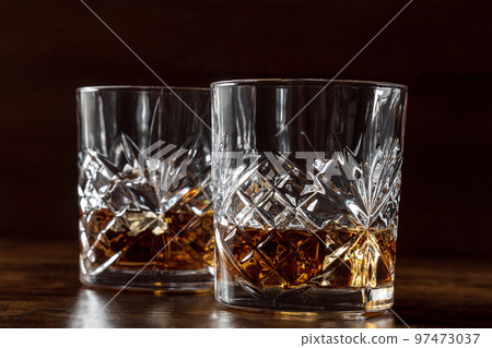 Whiskey in glasses with ice. Bourbon whisky on rocks on a dark background 97473037
