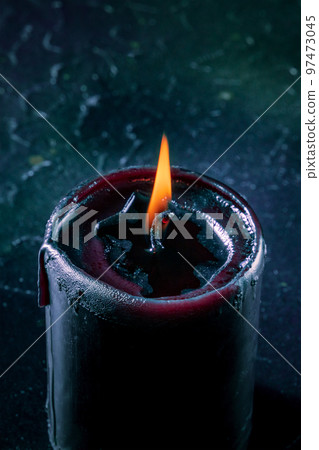 Burning candle on a dark background Burning candle on a dark background 97473045
