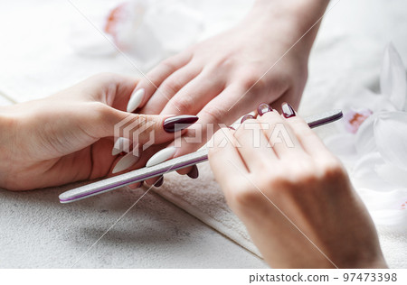 Hands of a young woman with white manicure on nails Hands of a young woman with white manicure on nails 97473398