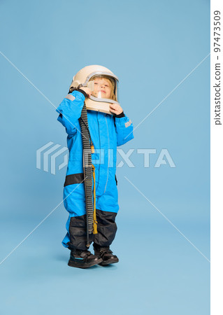 Portrait of little boy, child posing in astronaut costume over blue studio background. Dreams and imagination Portrait of little boy, child posing in astronaut costume over blue studio background. Dreams and imagination 97473509
