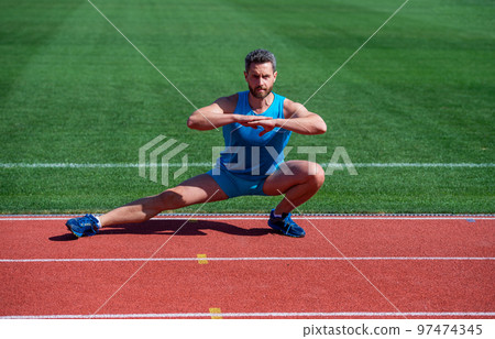Athletic runner doing stretching exercise preparing for morning workout, warming up 97474345
