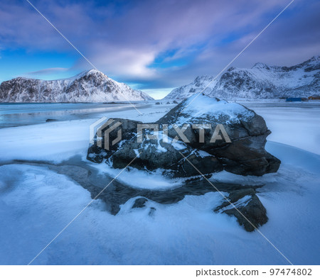 Sandy beach with blue sea reflected in water and rocks in snow Sandy beach with blue sea reflected in water and rocks in snow 97474802