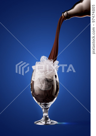 Frothy drink. Imitation of stream of dark stout pours into beer glass over dark blue background. Concept of creativity, imagination, Oktoberfest, ad Frothy drink. Imitation of stream of dark stout pours into beer glass over dark blue background. Concept of creativity, imagination, Oktoberfest, ad 97474805