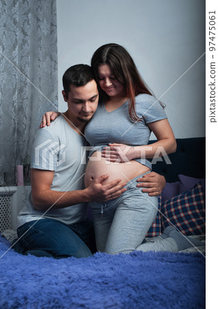 Loving couple in anticipation of baby. Man kisses belly of pregnant woman.. Loving couple in anticipation of baby. Man kisses belly of pregnant woman.. 97475061