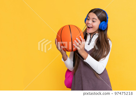 shocked kid in headphones with school backpack and basketball ball on yellow background shocked kid in headphones with school backpack and basketball ball on yellow background 97475218