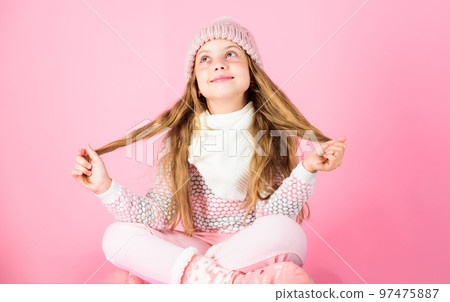 Winter fashion concept. Girl long hair relaxing pink background. Kid smiling fashion model. Kid girl wear cute knitted fashionable hat and comfortable cozy clothes. Winter fashion for children Winter fashion concept. Girl long hair relaxing pink background. Kid smiling fashion model. Kid girl wear cute knitted fashionable hat and comfortable cozy clothes. Winter fashion for children 97475887