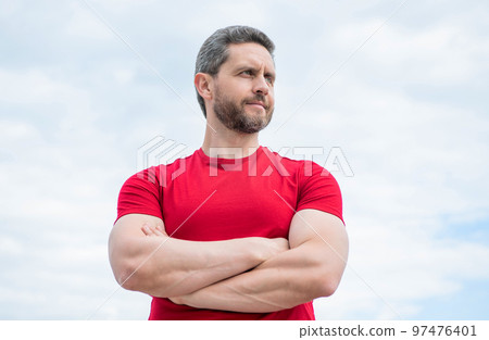 confident guy in red shirt crossed hands on sky background confident guy in red shirt crossed hands on sky background 97476401