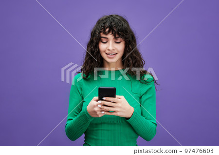 Young brunette woman in green pullover scrolling in smartphone Young brunette woman in green pullover scrolling in smartphone 97476603