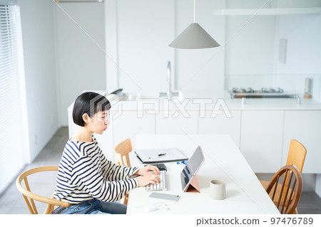 在房間裡的桌子旁工作的年輕女人 97476789